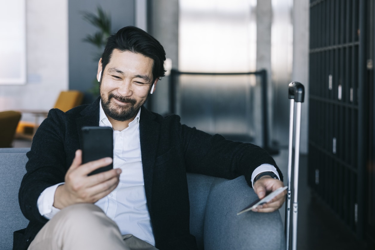 Businessman on his way to a company trip while holding a mobile phone.